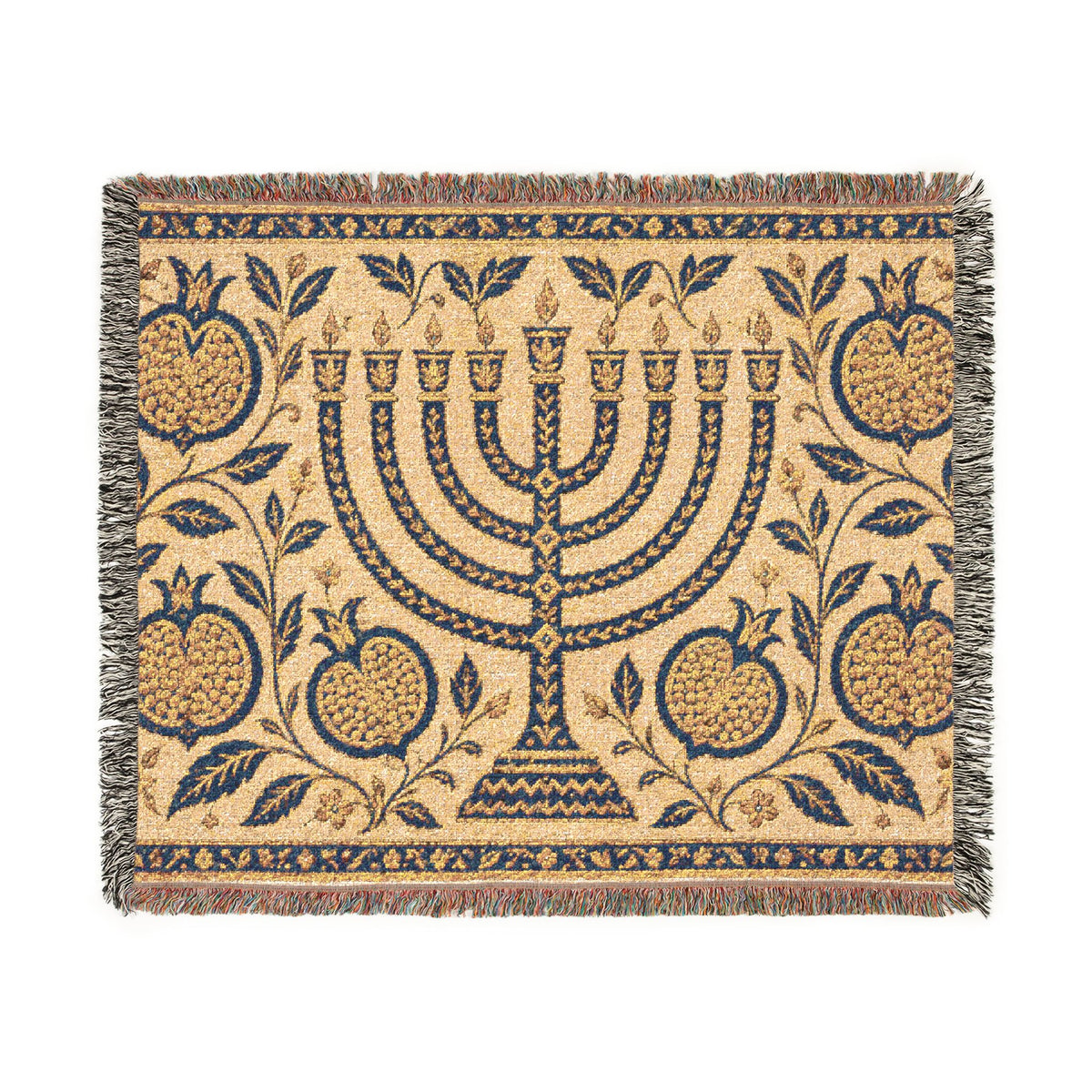 A rectangular woven textile with fringe on all sides, featuring a central menorah surrounded by pomegranate motifs and floral vines on a warm beige background. The design is primarily navy blue with tan and muted red accents in the fringe and border details.