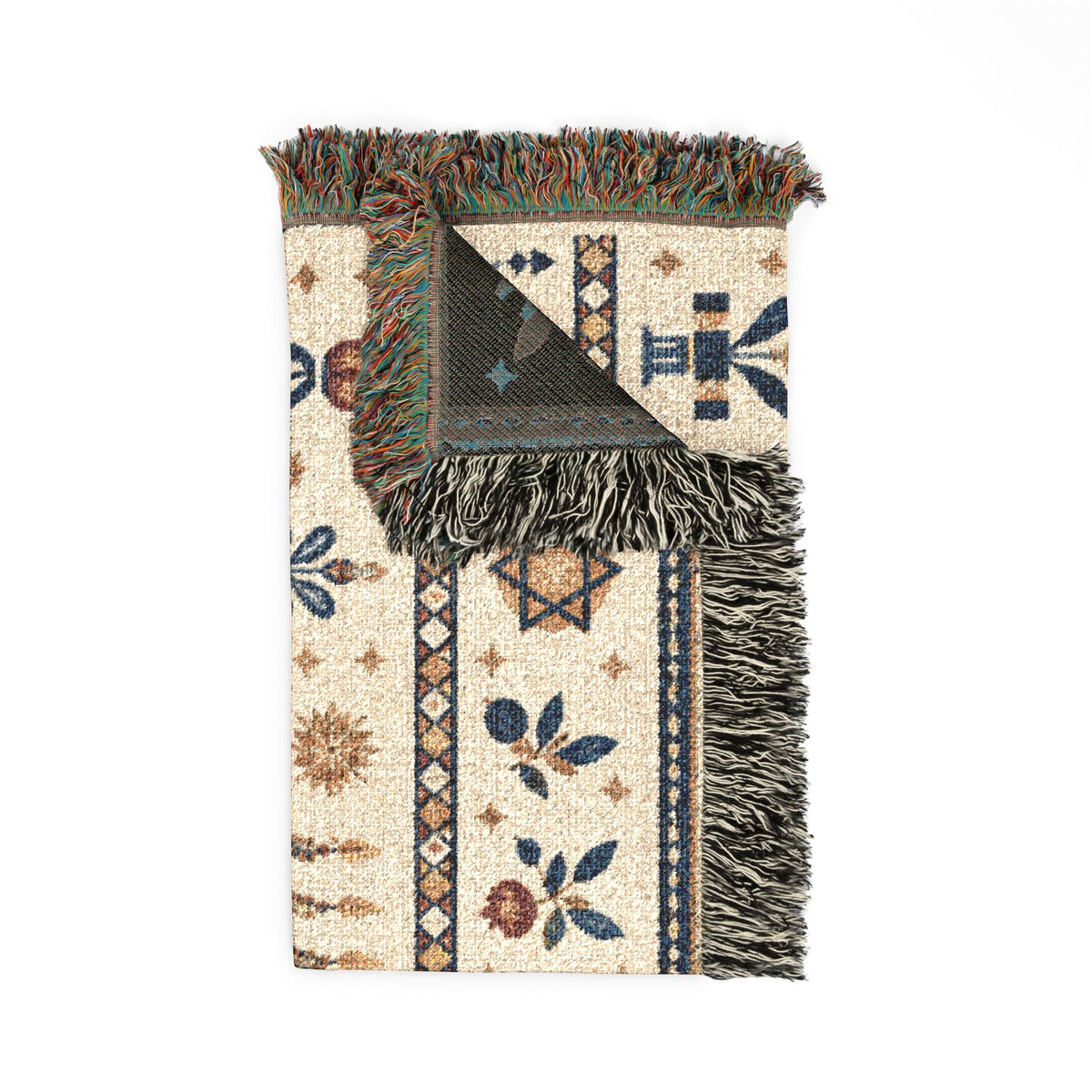 A folded woven throw blanket with fringe, featuring a cream base with blue, brown, and green geometric and floral patterns, shown on a plain white background.