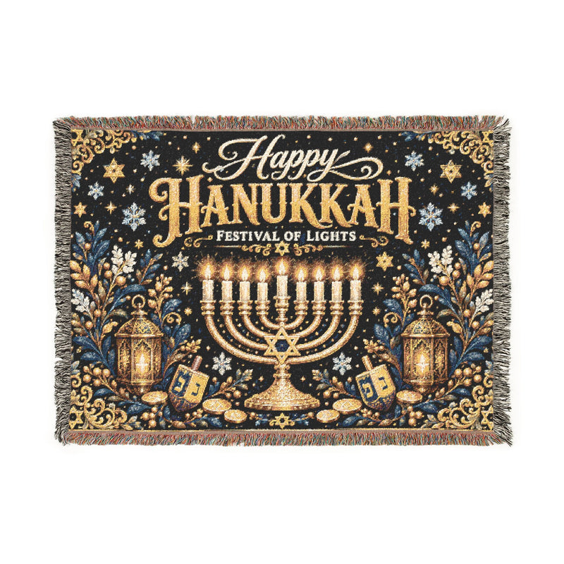 A rectangular woven tapestry with fringe on the edges, featuring a Hanukkah design. The tapestry has a dark navy blue background decorated with gold and silver lettering that reads 'Happy Hanukkah Festival of Lights', a golden menorah in the center, lanterns, stars, and dreidels.