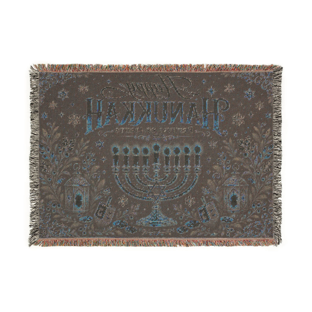 A rectangular woven throw blanket with fringe on all sides, featuring a dark brown background with a blue and beige menorah, stars, floral motifs, and Hebrew text reading 'Shin L'Chaim' on a white background.