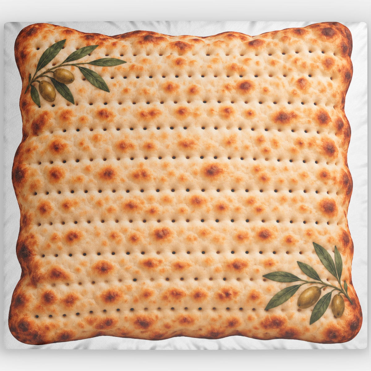 A square decorative pillow featuring a realistic printed design of a matzah cracker with toasted spots and olive branch illustrations in the top-left and bottom-right corners, shown against a white background.