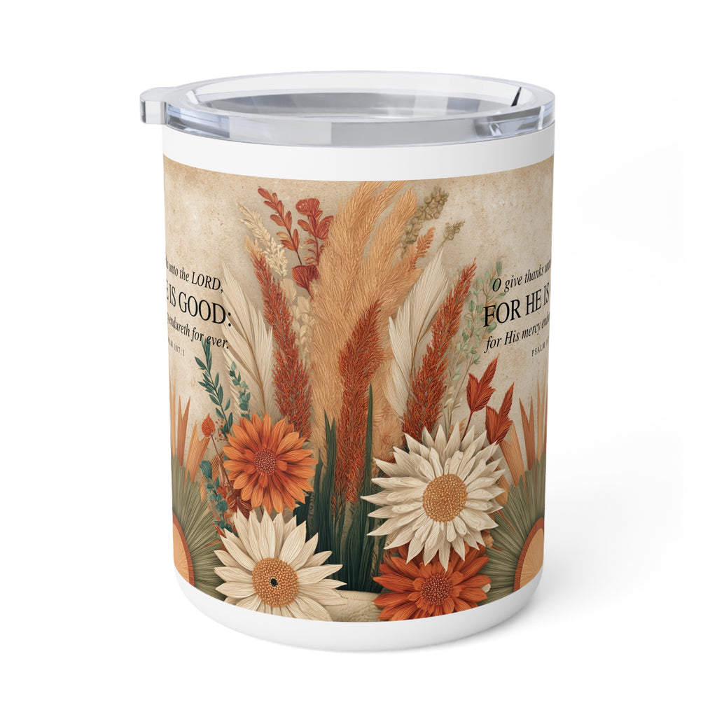 A white insulated tumbler with a clear lid, featuring a printed autumn floral design with orange and cream flowers, beige pampas grass, and Bible verse text on a warm beige background.