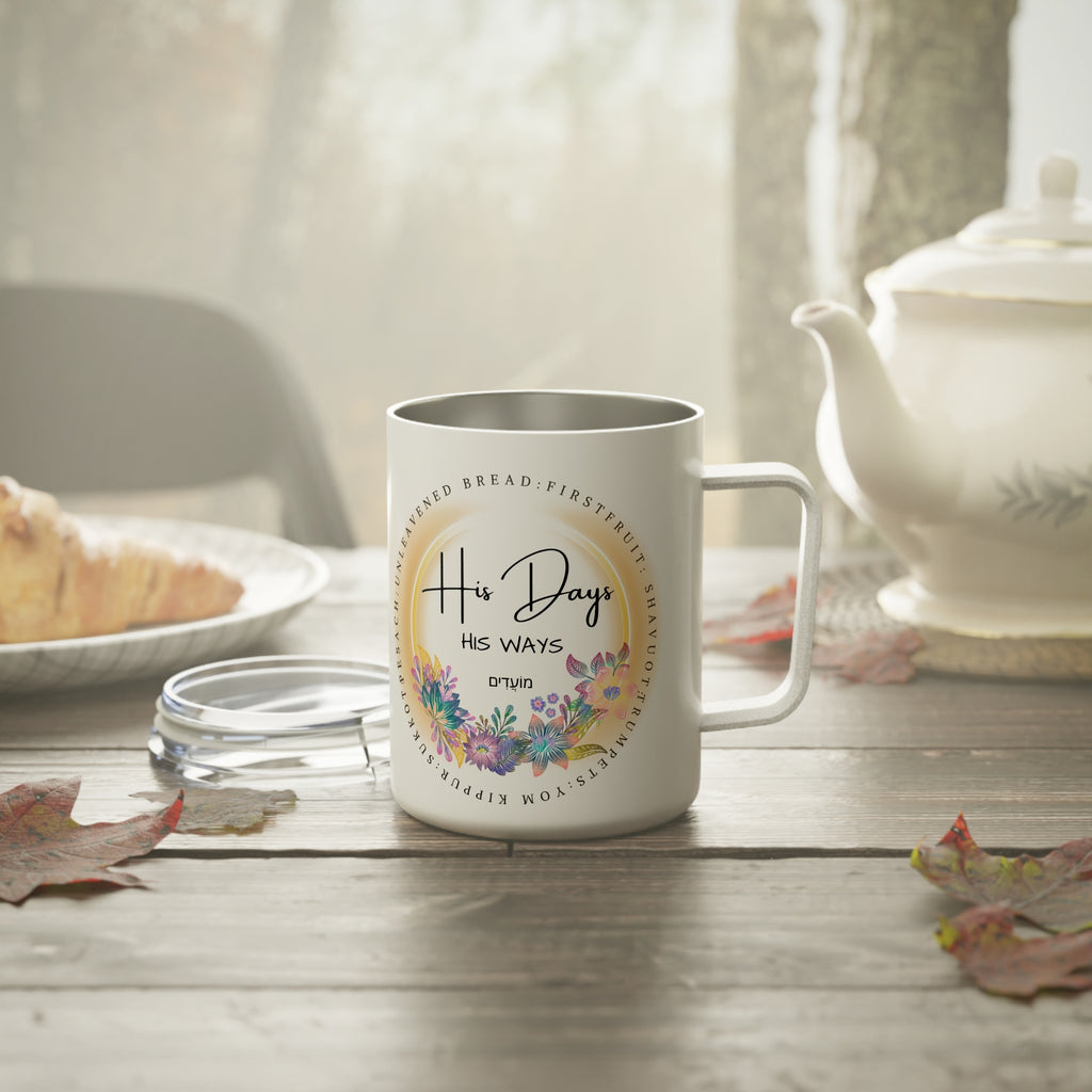 White mug with 'His Days His Ways' floral design on a wooden table with a teapot and croissant in the background.