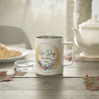 White mug with 'His Days His Ways' floral design on a wooden table with a teapot and croissant in the background.