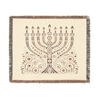 A square woven throw blanket with fringed edges, featuring a brown menorah and ornamental scroll pattern on a warm cream background.