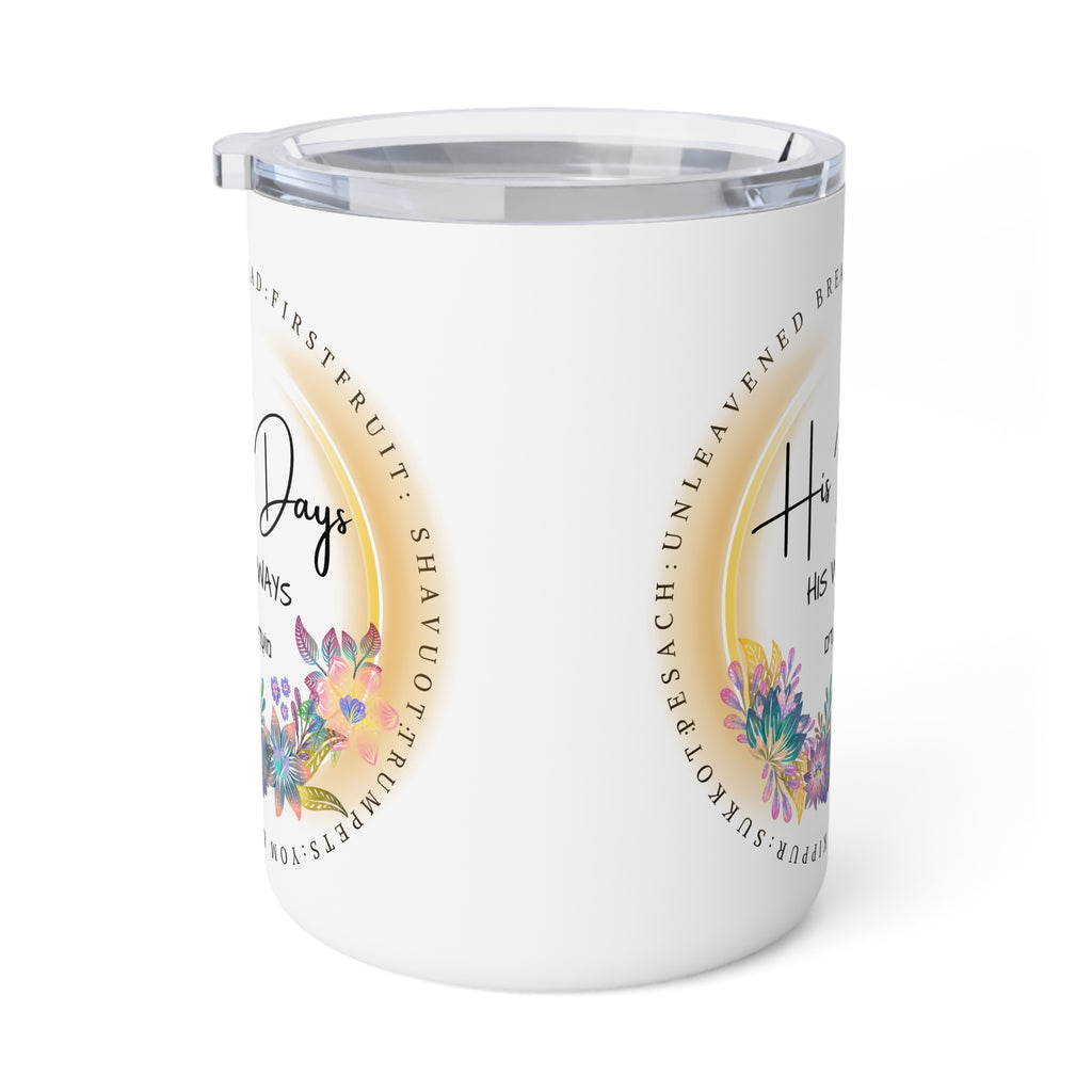 A white insulated tumbler with a clear lid, featuring a circular gold-toned graphic with floral illustrations and text on the side.