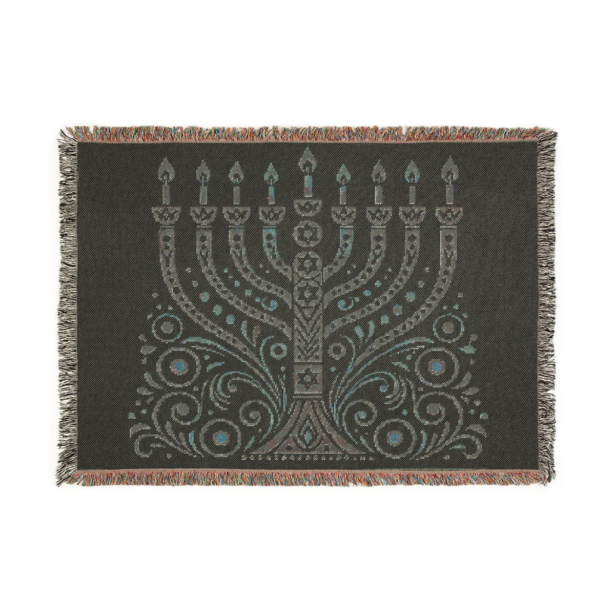 A rectangular woven throw blanket with fringe on all sides, featuring a large menorah and ornate scrollwork design in light gray and turquoise on a dark charcoal background.