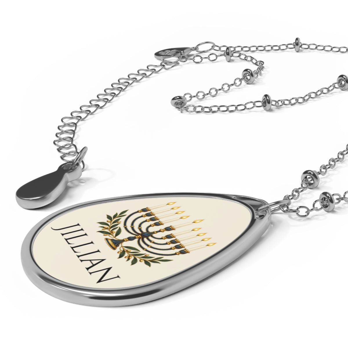 A silver teardrop pendant necklace featuring a custom printed design with the name 'JILLIAN' in black, a menorah in gold, and green olive branches, displayed on a clean white background.