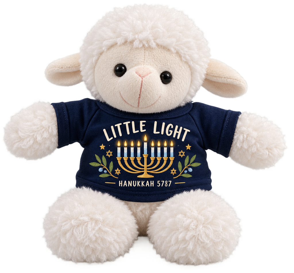 A plush white sheep toy wearing a navy blue shirt with a Hanukkah graphic that reads 'LITTLE LIGHT' and 'HANUKKAH 5787' with a gold menorah and blue candles.