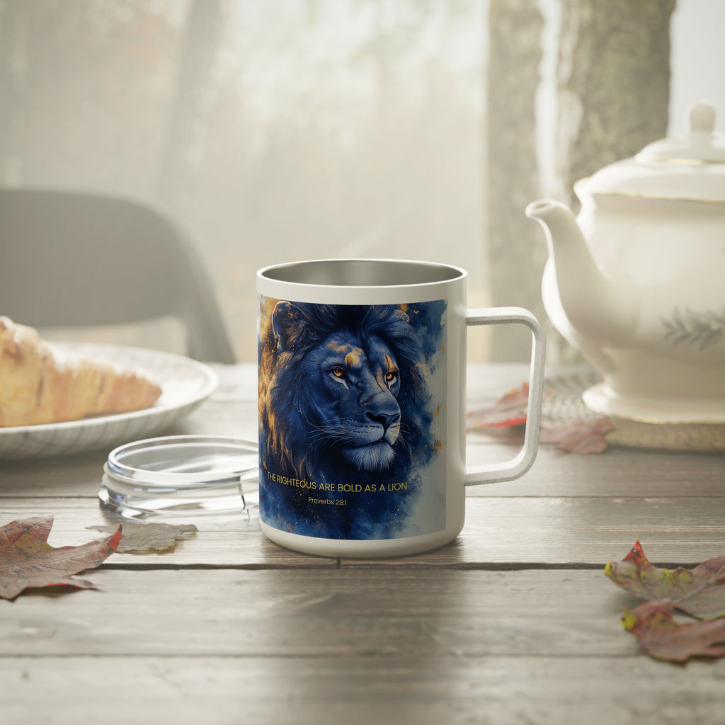 A white ceramic mug with a printed blue lion illustration and the quote 'THE RIGHTOUS ARE BOLD AS A LION Proverbs 16:42' sits on a wooden table in a cozy kitchen setting with a teapot, plate, and leaves.