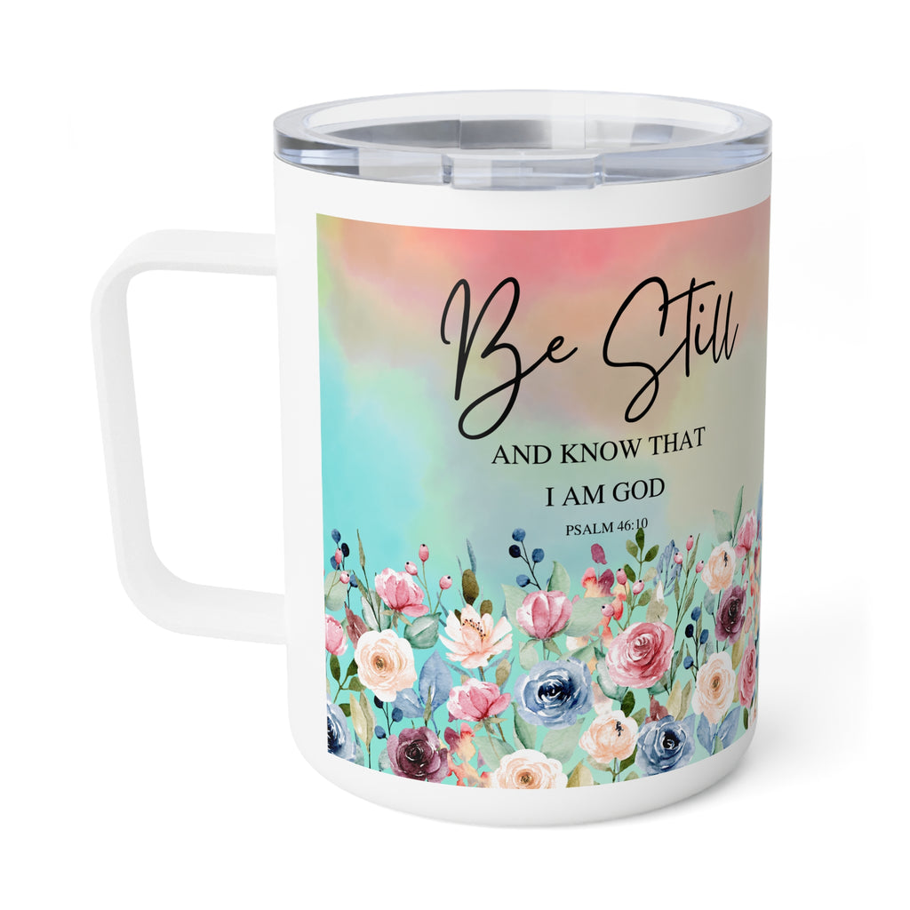 A white stainless steel travel mug with a clear lid, featuring a colorful floral design and the text 'Be Still AND KNOW THAT I AM GOD PSALM 40:1' on the front, set against a plain white background.