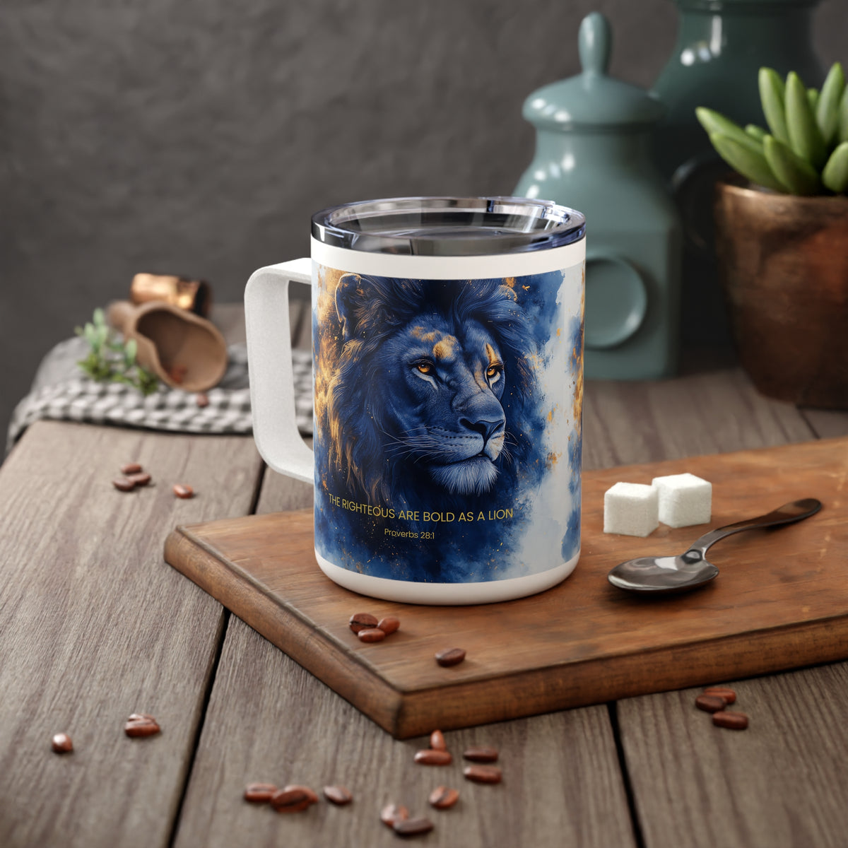 A white stainless steel mug with a printed blue lion illustration and the quote 'THE RIGHTEOUS ARE BOLD AS A LION - Proverbs 16:32' sits on a wooden cutting board on a rustic table. The mug is styled with coffee beans, sugar cubes, a spoon, and background kitchen items.