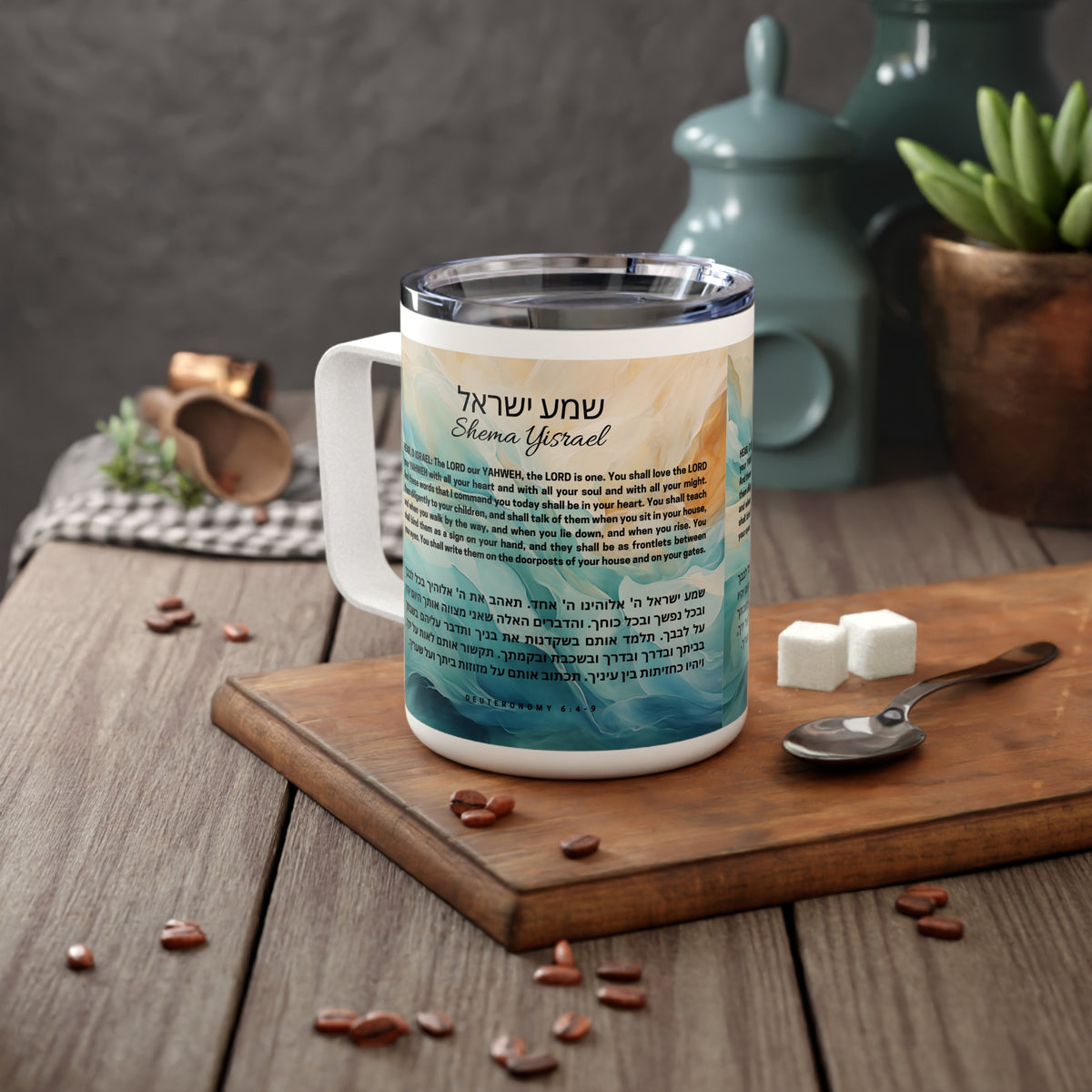 A white stainless steel mug with a clear lid sits on a wooden cutting board on a rustic table. The mug features a printed design with Hebrew text and a scenic landscape illustration in blue and beige tones.
