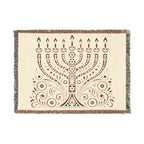 A rectangular woven throw blanket featuring a brown menorah design on a cream background, finished with fringed edges.