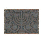 A rectangular woven throw blanket featuring a central menorah motif with pomegranate and floral patterns, finished with fringed edges in a muted blue, gray, and brown palette.