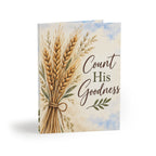 A greeting card featuring an illustration of a tied bundle of golden wheat stalks on a cream watercolor background with blue sky accents. The text 'Count His Goodness' is printed on the front.