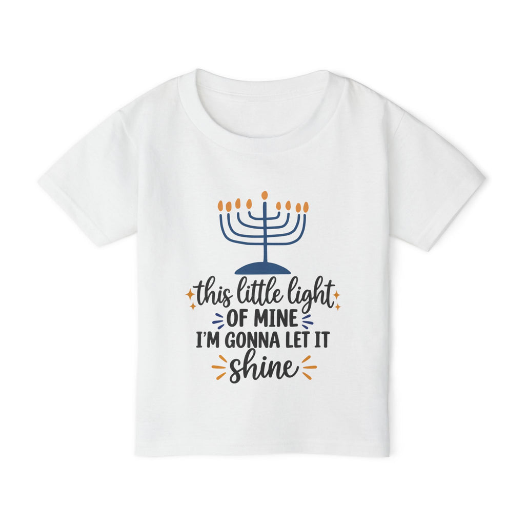 A white short-sleeve kids' t-shirt with a Hanukkah graphic on the front. The graphic features a blue menorah with orange flames and the text 'this little light OF MINE I'M GONNA LET IT shine' in dark blue and orange cursive fonts.