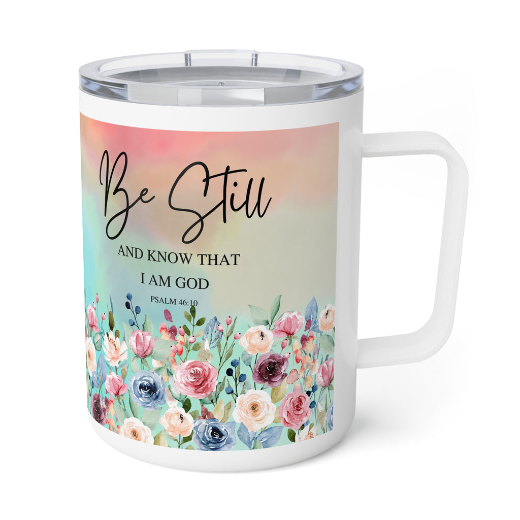 A white stainless steel travel mug with a clear lid and handle, featuring a printed design with the words 'Be Still AND KNOW THAT I AM GOD' and a pastel floral border.