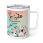 A white stainless steel travel mug with a clear lid and handle, featuring a printed design with the words 'Be Still AND KNOW THAT I AM GOD' and a pastel floral border.