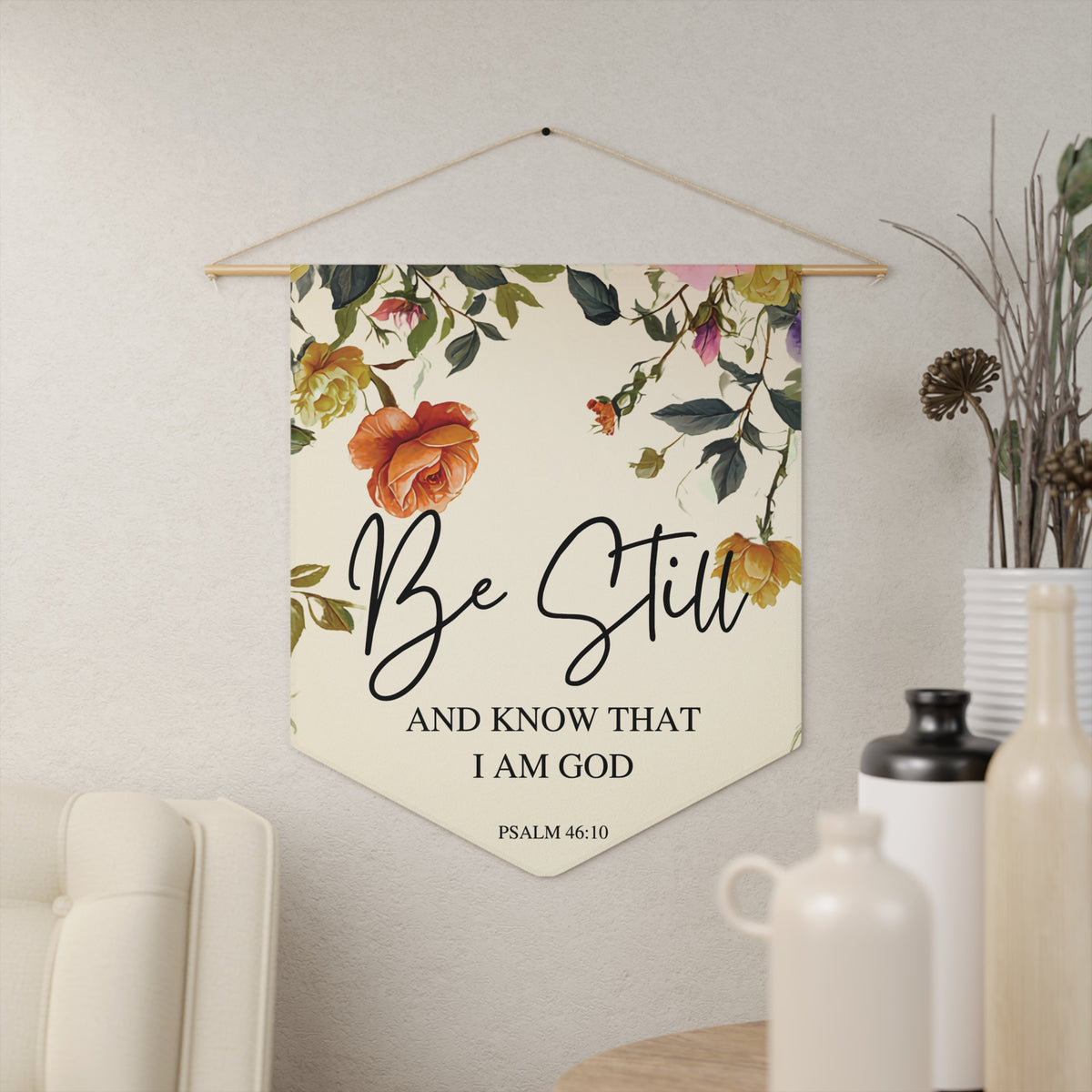 Cream Be Still and Know That I Am God wall pennant with watercolor roses, Psalm 46:10, hanging on a cream wall beside vases