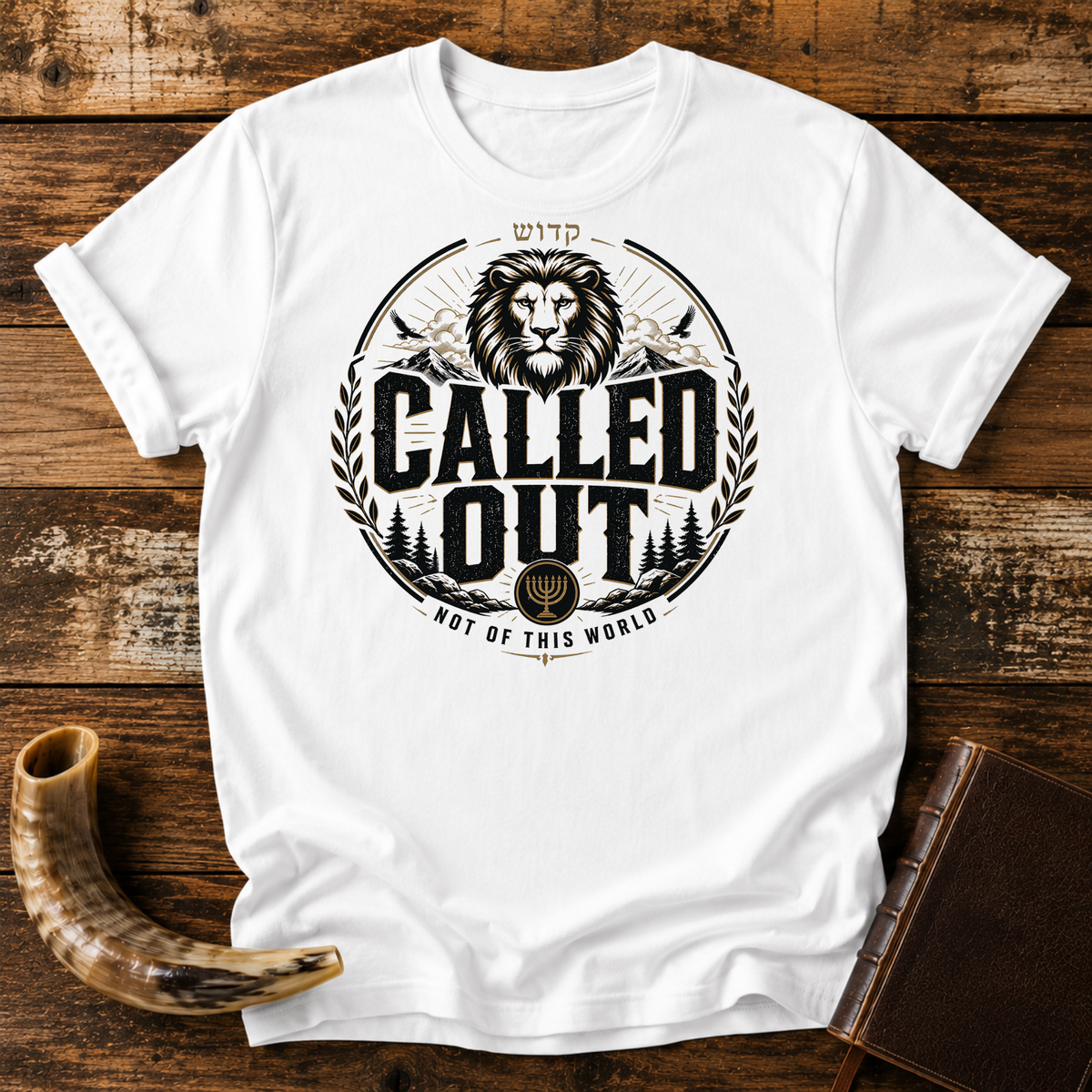White t-shirt with a CALLED OUT lion badge with Hebrew lettering, a menorah and NOT OF THIS WORLD, laid flat with a shofar and a leather book