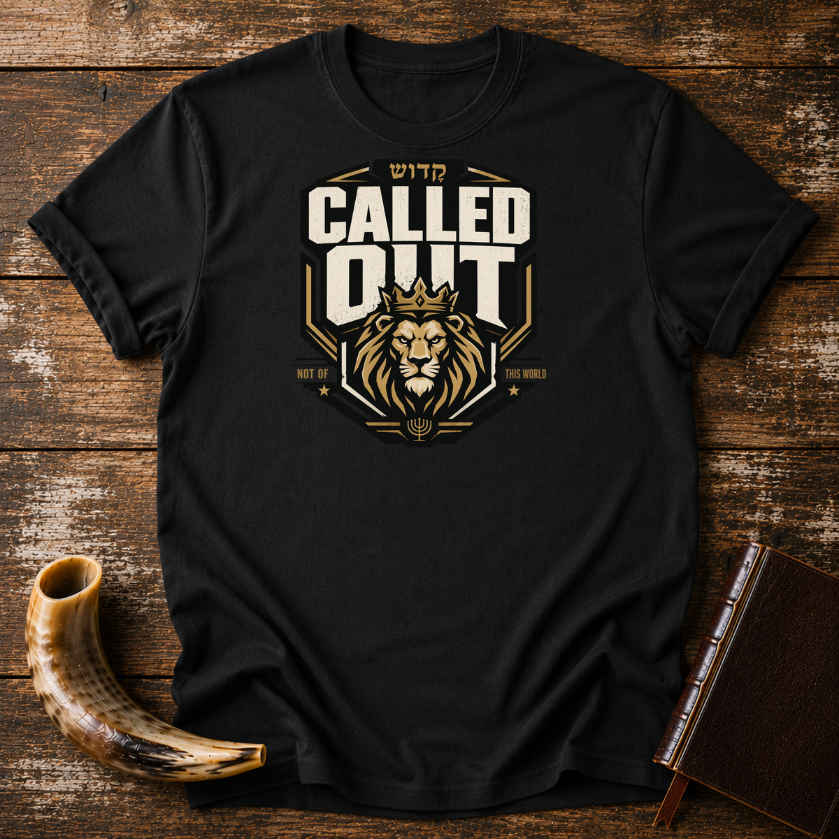 Black Called Out tee with a crowned lion badge and Hebrew lettering, laid flat with a shofar and a leather-bound book