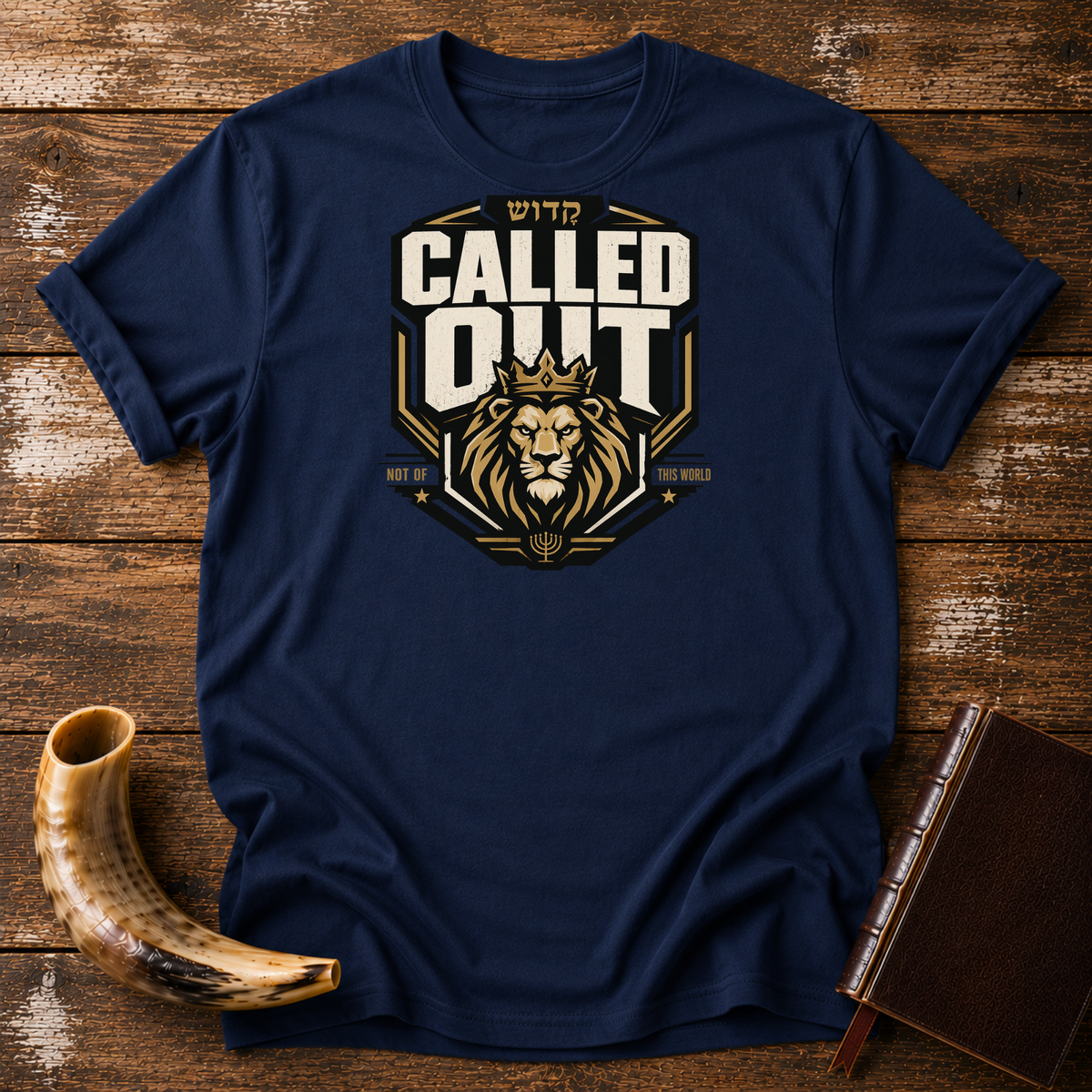 Navy Called Out tee with a crowned lion badge and Hebrew lettering, laid flat with a shofar and a leather-bound book