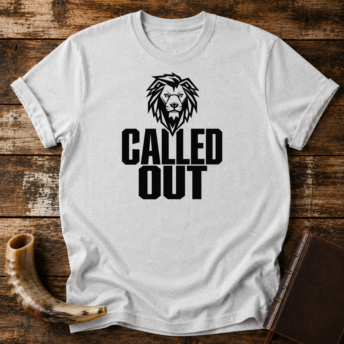 Sport grey t-shirt with a black lion head above bold CALLED OUT text, laid flat with a shofar and a leather book