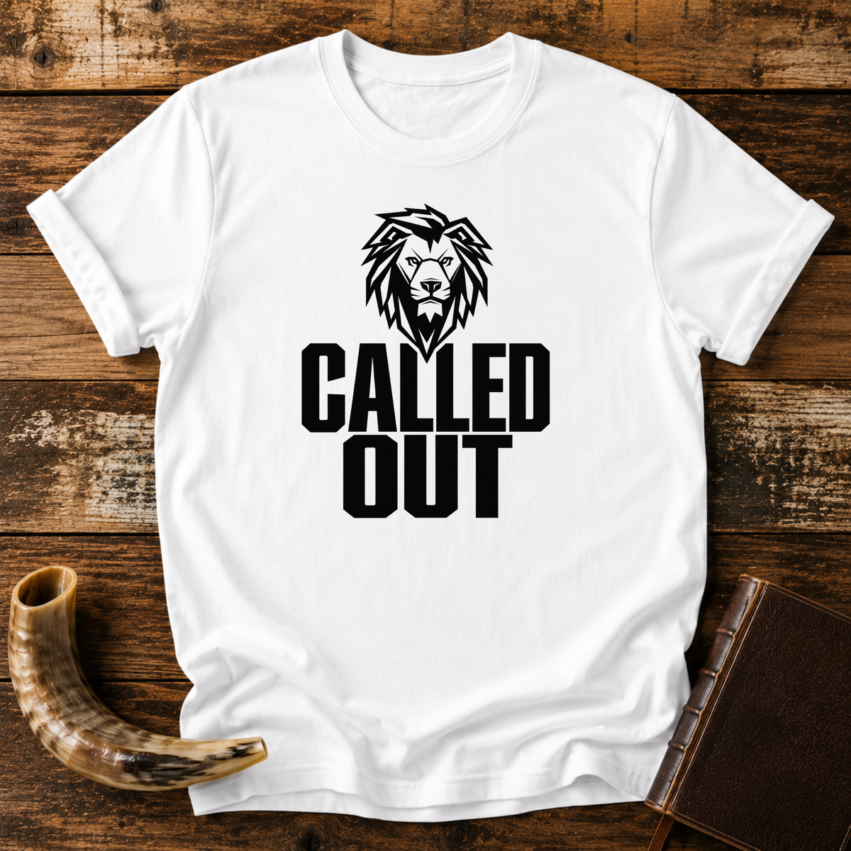 White t-shirt with a black lion head above bold CALLED OUT text, laid flat with a shofar and a leather book