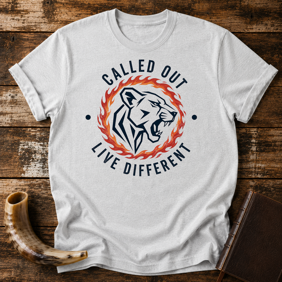 Sport grey t-shirt with a roaring lioness in a ring of fire with CALLED OUT and LIVE DIFFERENT, laid flat with a shofar and a leather book