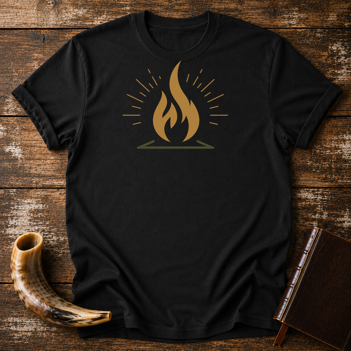 Black t-shirt with a gold flame graphic with radiating lines, laid flat with a shofar and a leather book