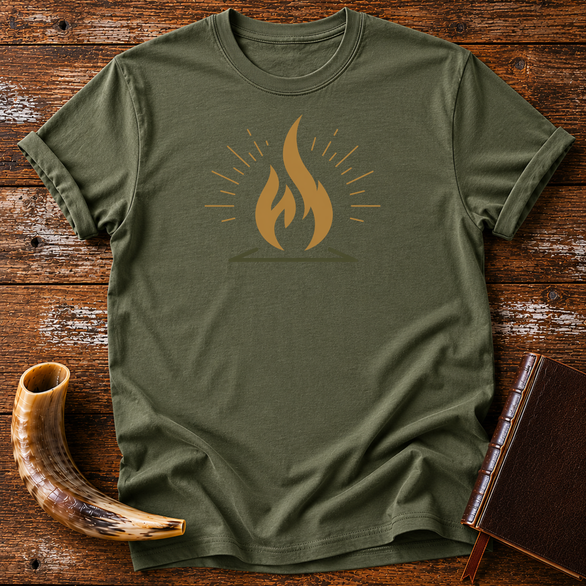 Military green t-shirt with a gold flame graphic with radiating lines, laid flat with a shofar and a leather book