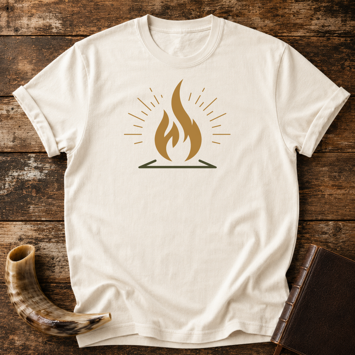 Natural cream t-shirt with a gold flame graphic with radiating lines, laid flat with a shofar and a leather book
