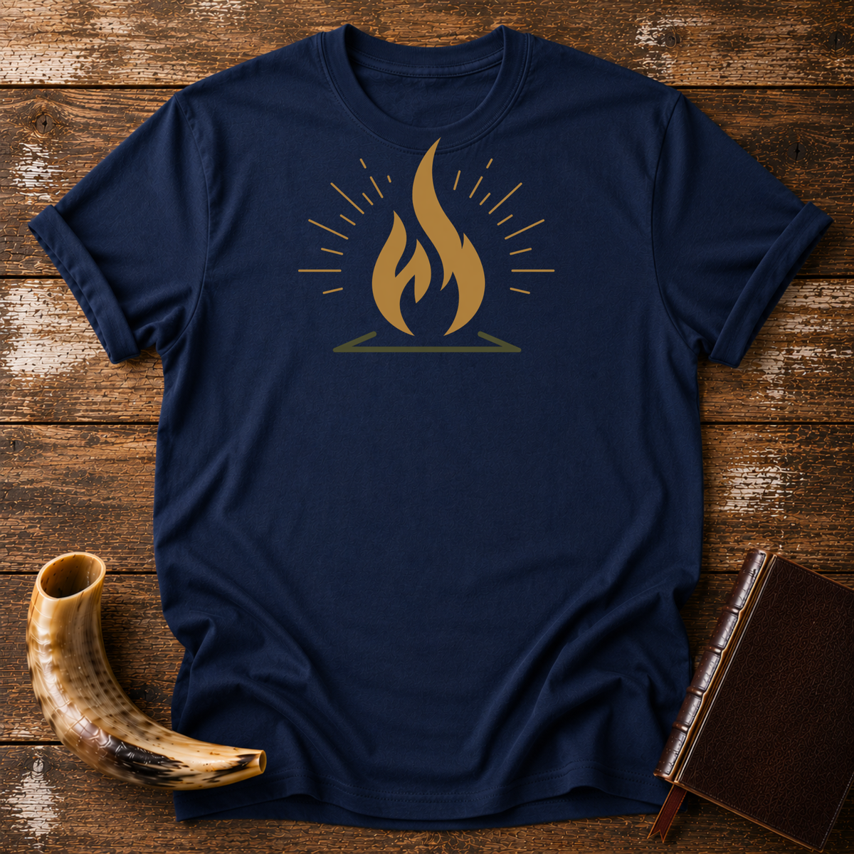 Navy t-shirt with a gold flame graphic with radiating lines, laid flat with a shofar and a leather book