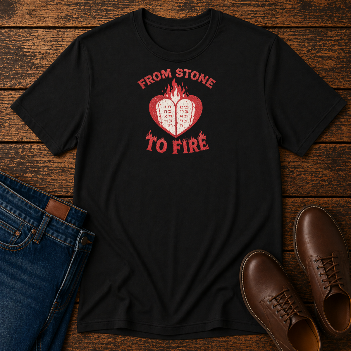 Black From Stone to Fire tee with stone tablets in a flaming heart, laid flat with jeans and brown shoes