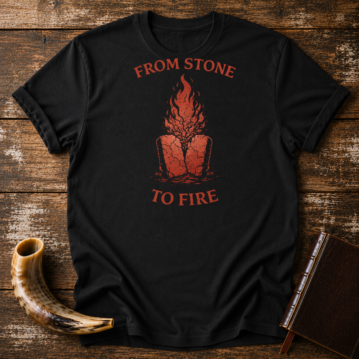 Black From Stone to Fire tee with red flames rising from stone tablets, laid flat with a shofar and a leather-bound book