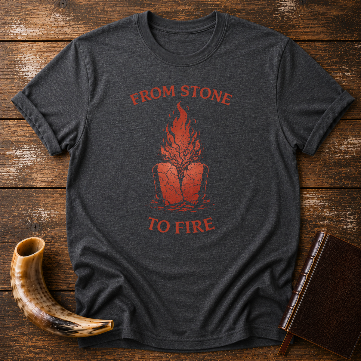 Dark heather From Stone to Fire tee with red flames rising from stone tablets, laid flat with a shofar and a leather-bound book