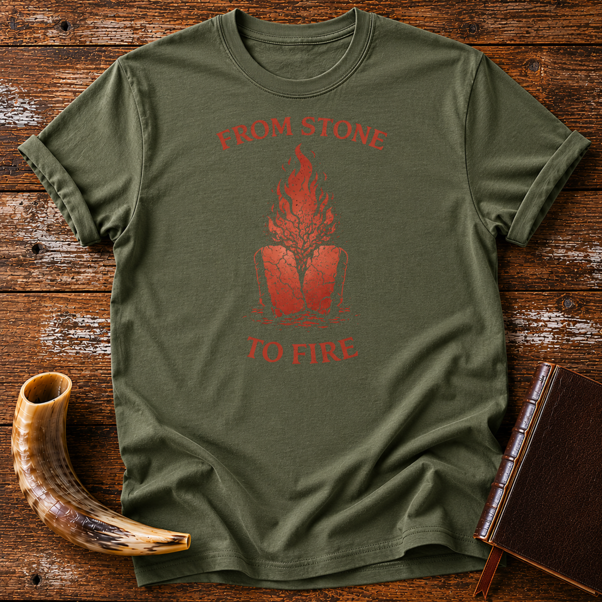 Military green From Stone to Fire tee with red flames rising from stone tablets, laid flat with a shofar and a leather-bound book