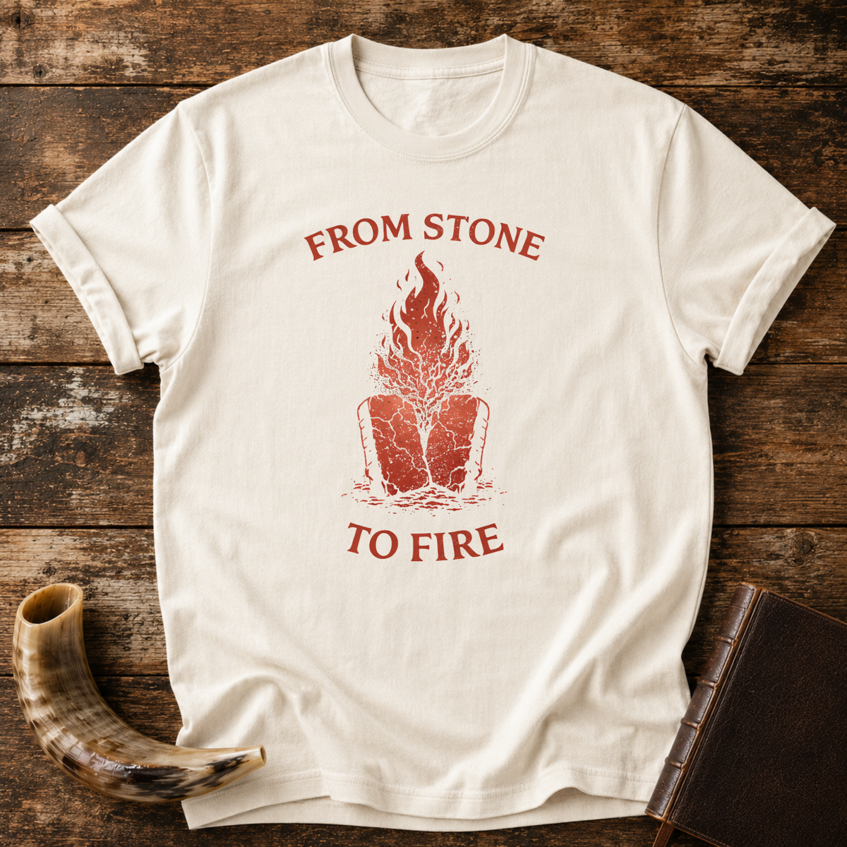 Natural From Stone to Fire tee with red flames rising from stone tablets, laid flat with a shofar and a leather-bound book