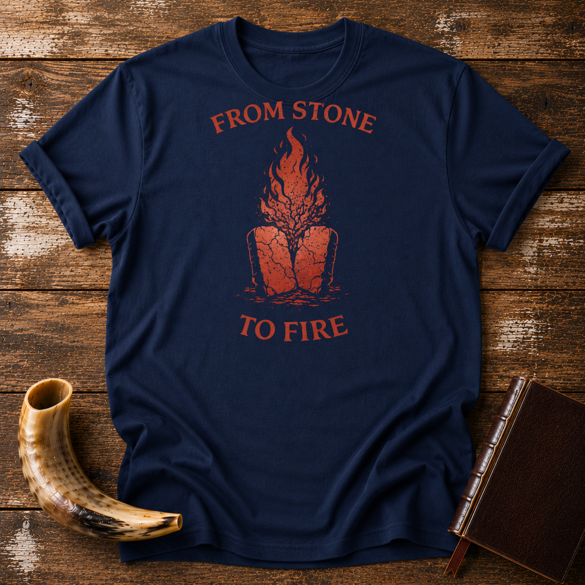 Navy From Stone to Fire tee with red flames rising from stone tablets, laid flat with a shofar and a leather-bound book