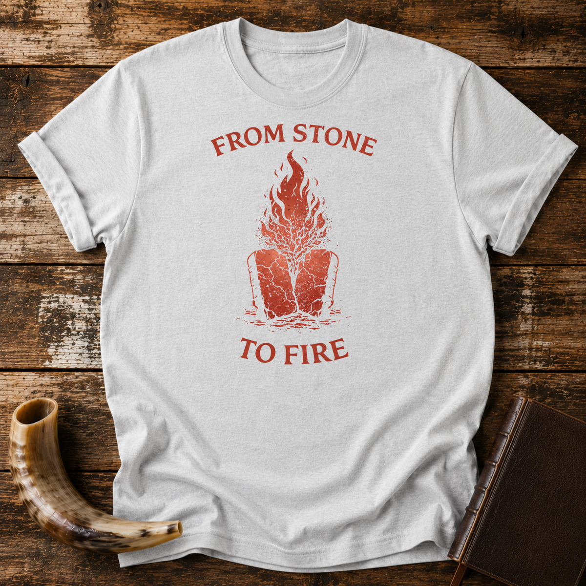 Sport grey From Stone to Fire tee with red flames rising from stone tablets, laid flat with a shofar and a leather-bound book