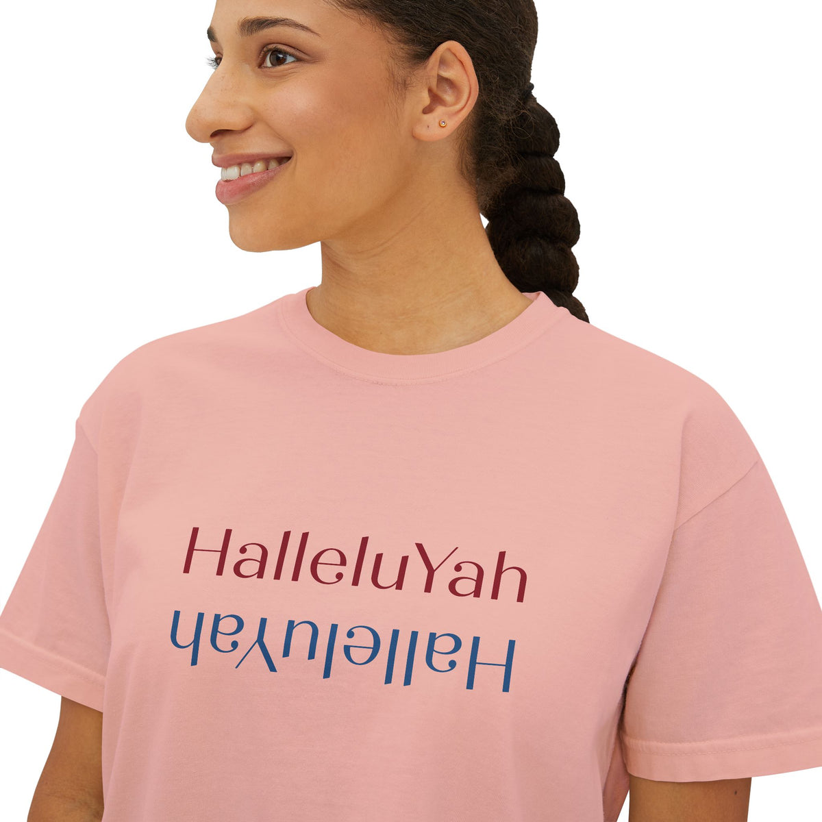 Close-up of a peachy pink boxy tee with red and blue mirrored HalleluYah lettering, worn by a woman