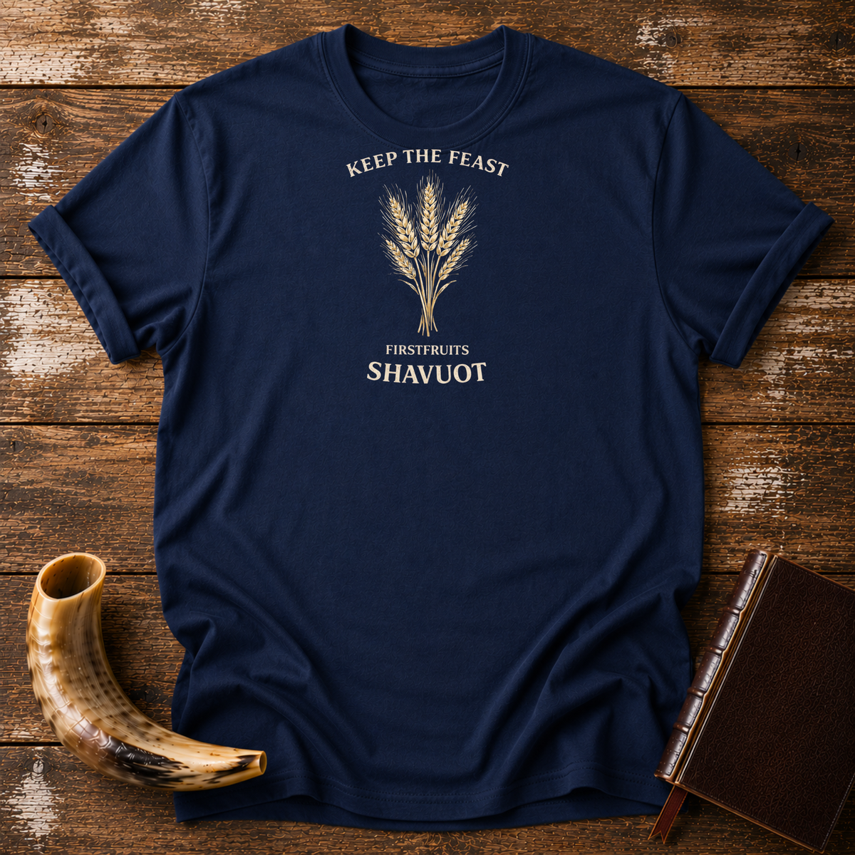 Navy Keep the Feast Firstfruits Shavuot tee with a cream wheat sheaf, laid flat with a shofar and a leather-bound book