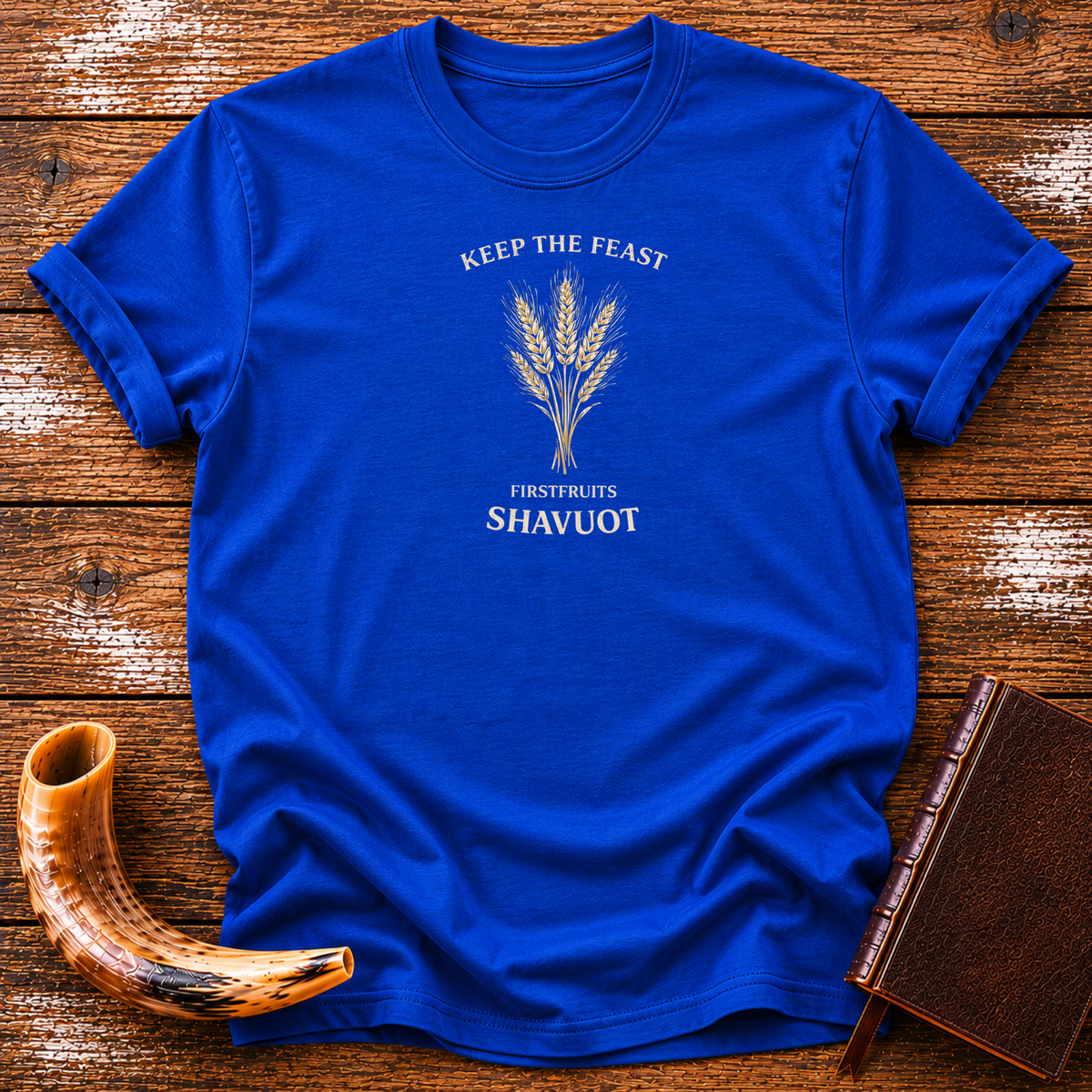 Royal blue Keep the Feast Firstfruits Shavuot tee with a cream wheat sheaf, laid flat with a shofar and a leather-bound book