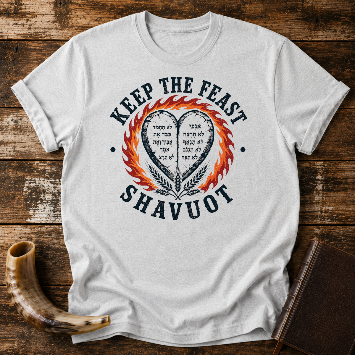 Sport grey t-shirt with KEEP THE FEAST SHAVUOT, Hebrew-lettered heart tablets, fire and wheat, laid flat with a shofar and a leather book