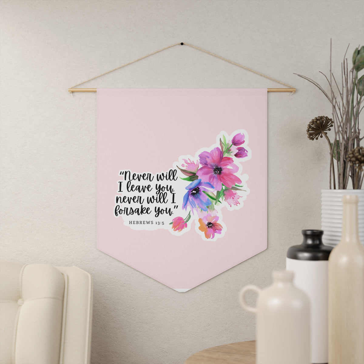 Pink Never will I leave you, never will I forsake you wall pennant with flowers, Hebrews 13:5, hanging on a cream wall beside vases