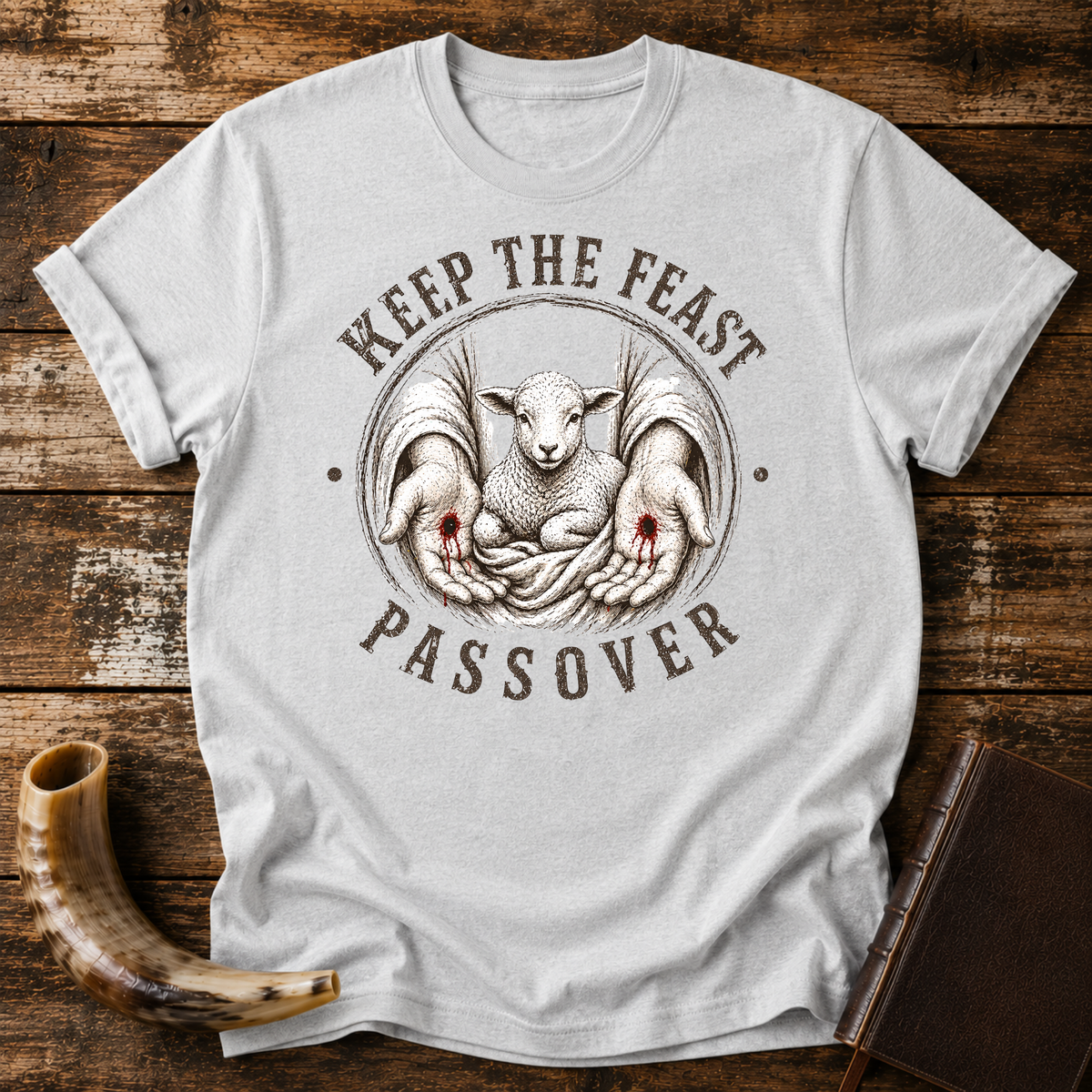 Sport grey t-shirt with KEEP THE FEAST PASSOVER around a lamb held in nail-scarred hands, laid flat with a shofar and a leather book