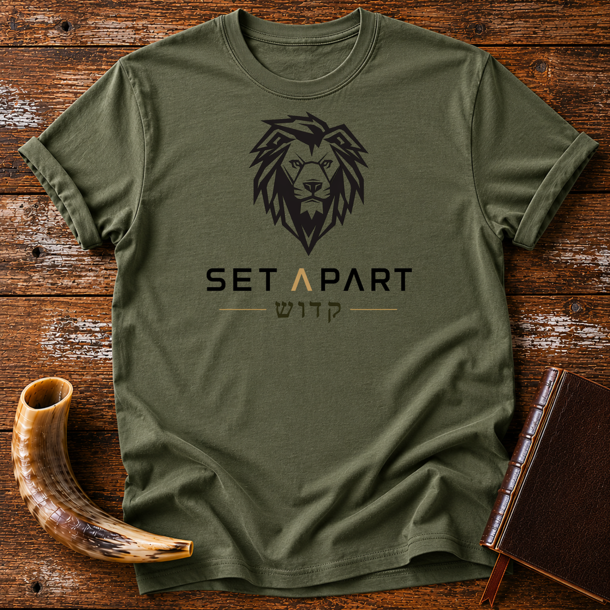 Military green t-shirt with a large black lion head above SET APART and Hebrew lettering, laid flat with a shofar and a leather book