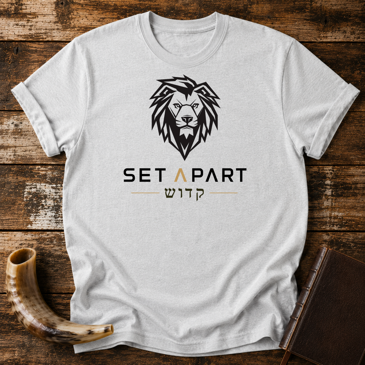 Sport grey t-shirt with a large black lion head above SET APART and Hebrew lettering, laid flat with a shofar and a leather book