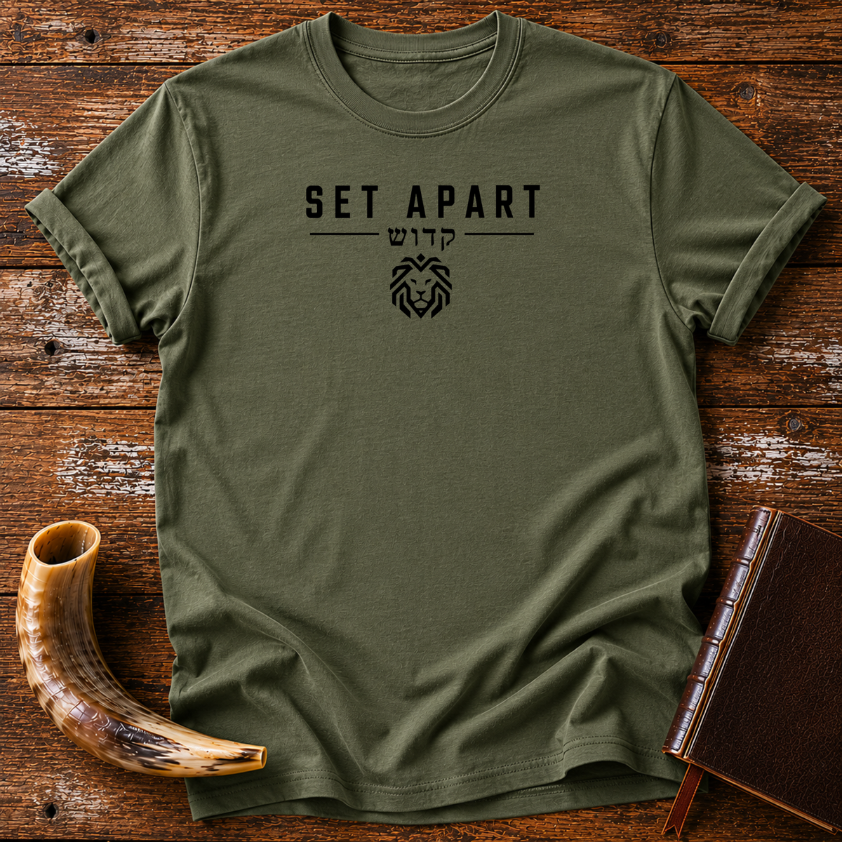 Military green t-shirt with SET APART, Hebrew lettering and a small geometric lion head, laid flat with a shofar and a leather book